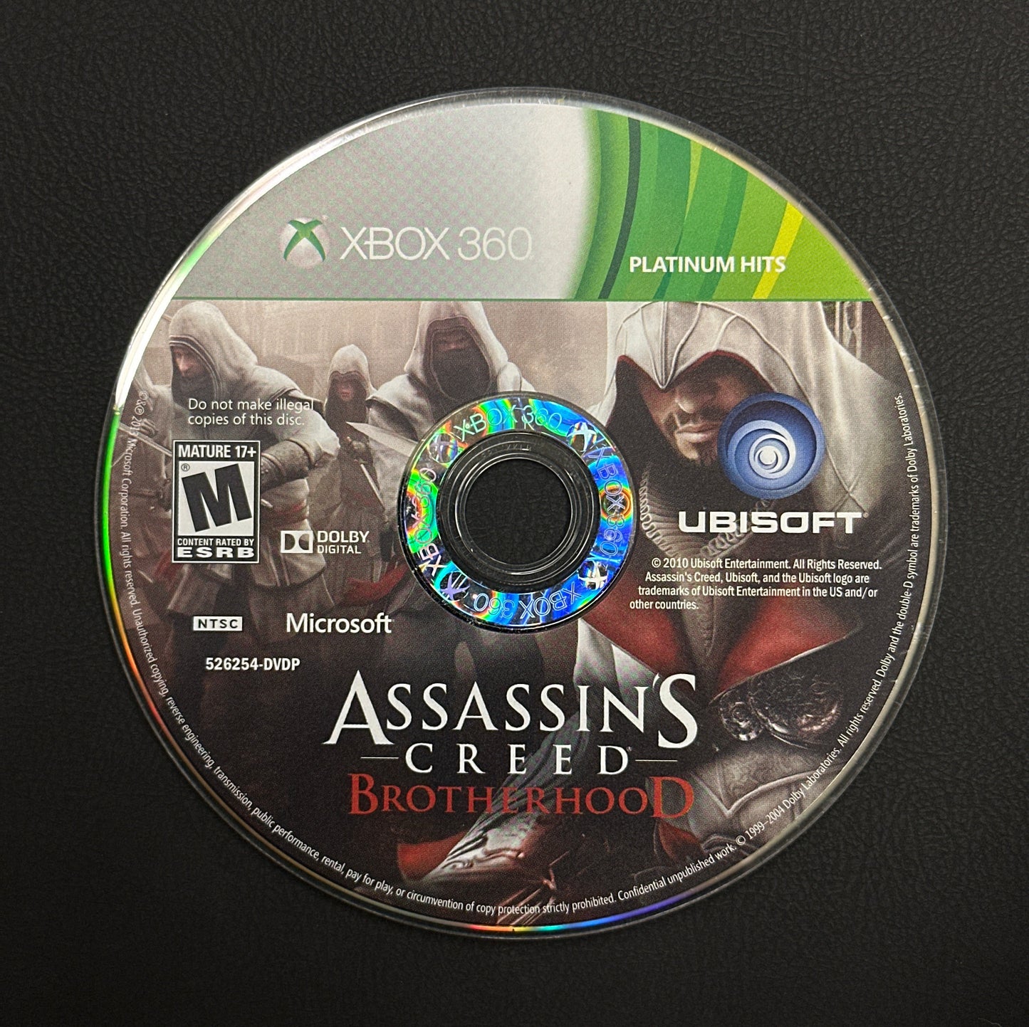 Assassin's Creed Brotherhood game disc on a black surface