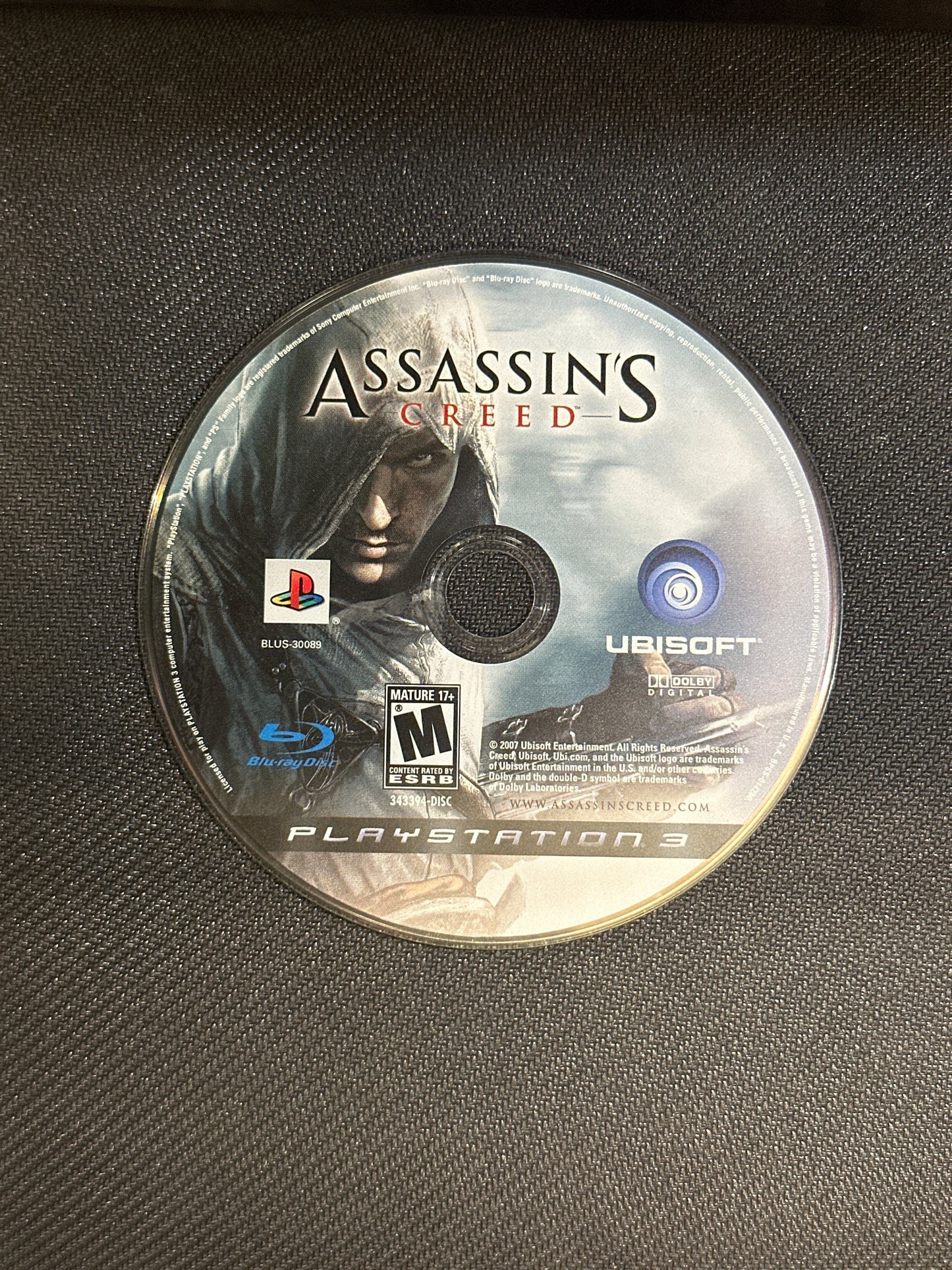 Assassin's Creed game disc on a textured surface