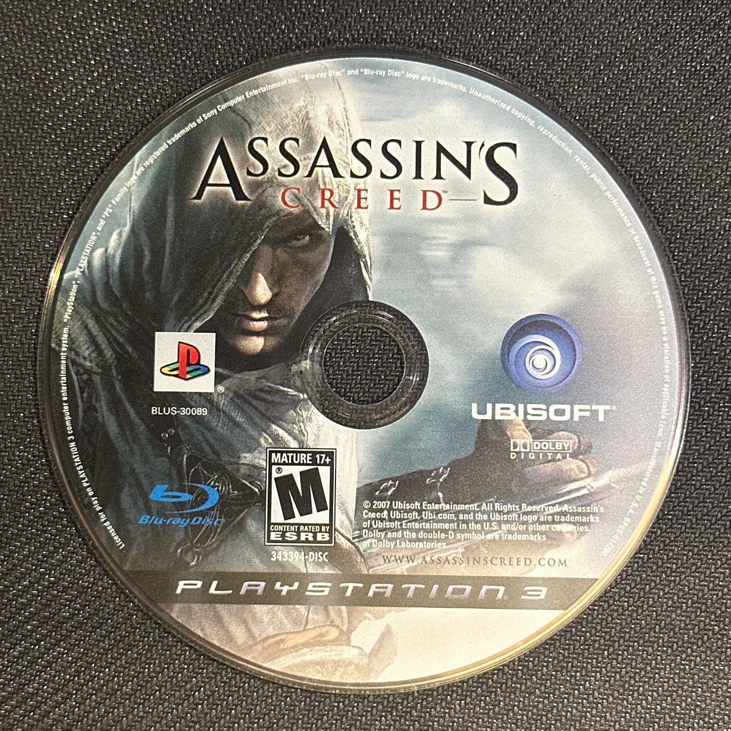 Assassin's Creed game disc on a textured surface