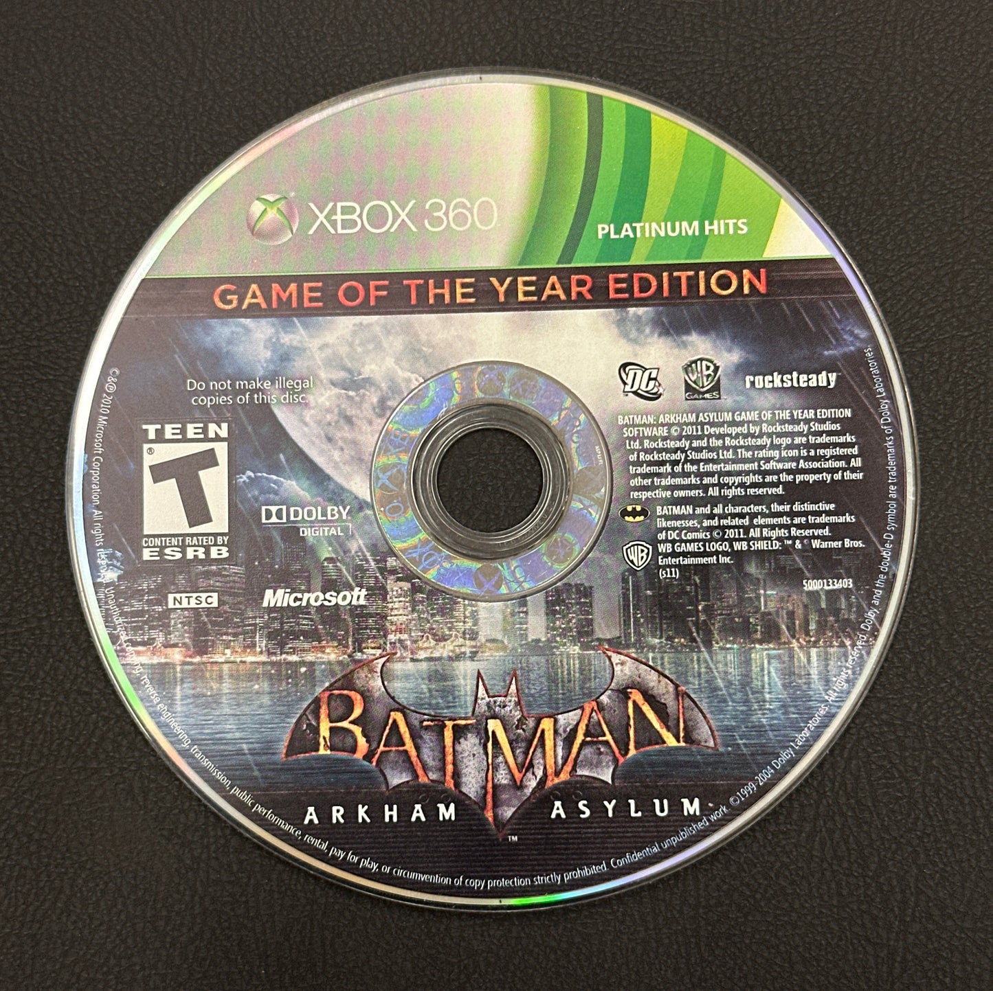 Batman Arkham Asylum game disc for Xbox 360 on a black background
