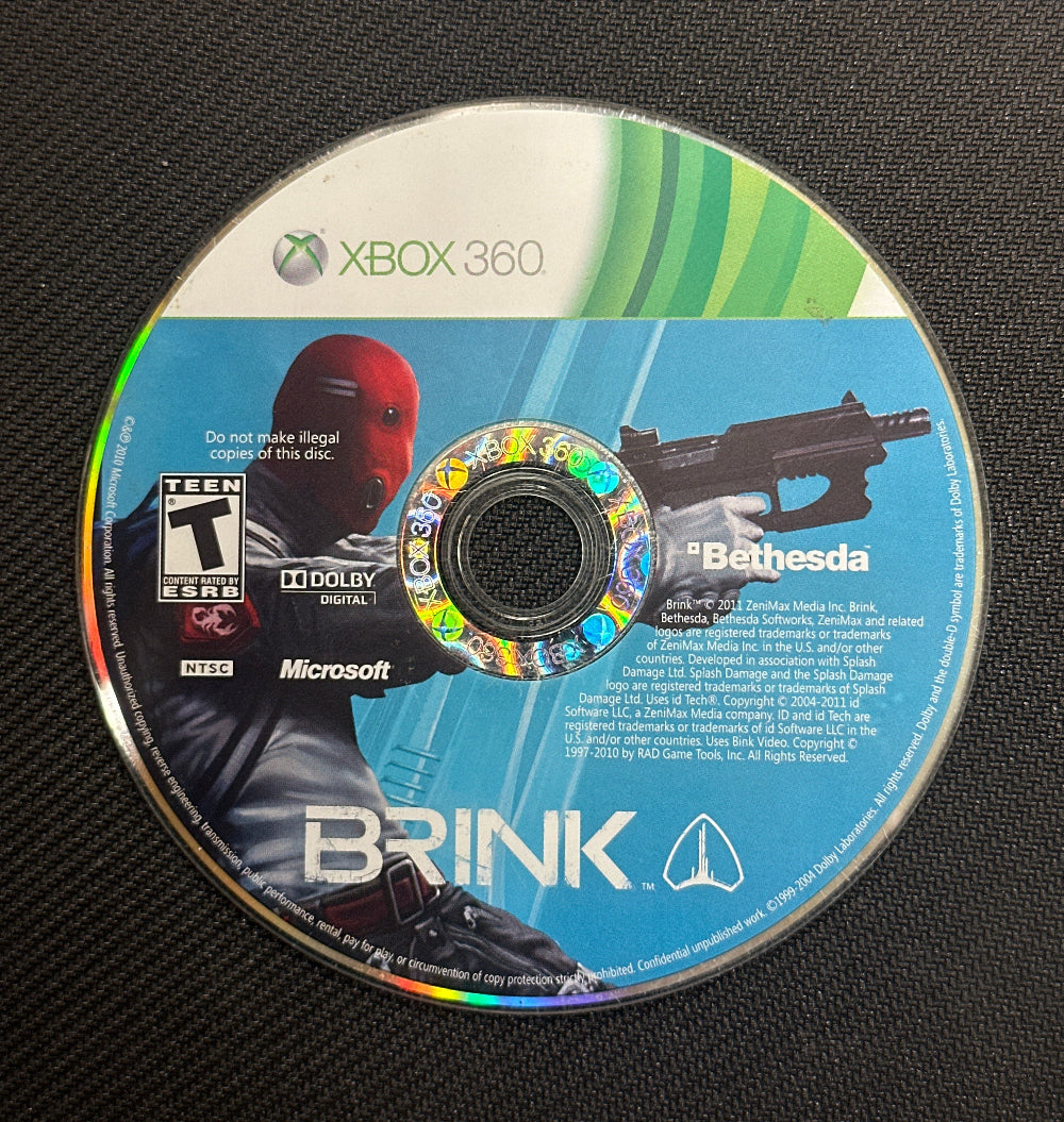 Game disc for 'Brink' on Xbox 360 with branding and graphics.