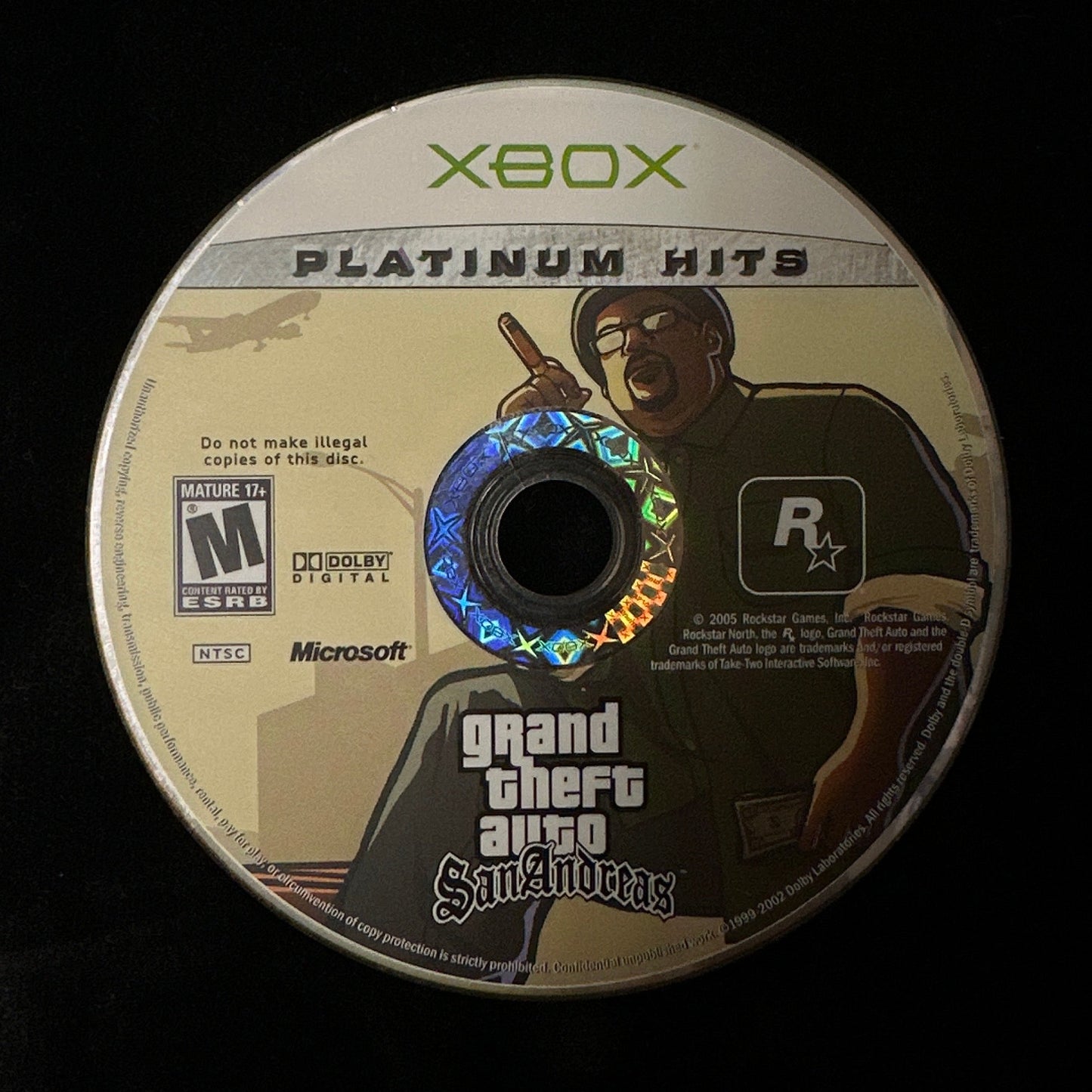 An Xbox Platinum Hits Grand Theft Auto: San Andreas game disc on a black background.
