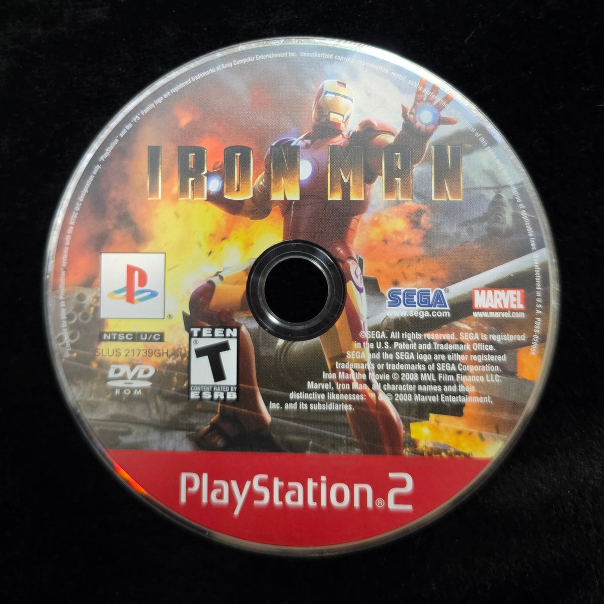 An Iron Man 2 PlayStation 2 game disc resting on a black fabric surface, showing the PlayStation and SEGA logos on the disc label.