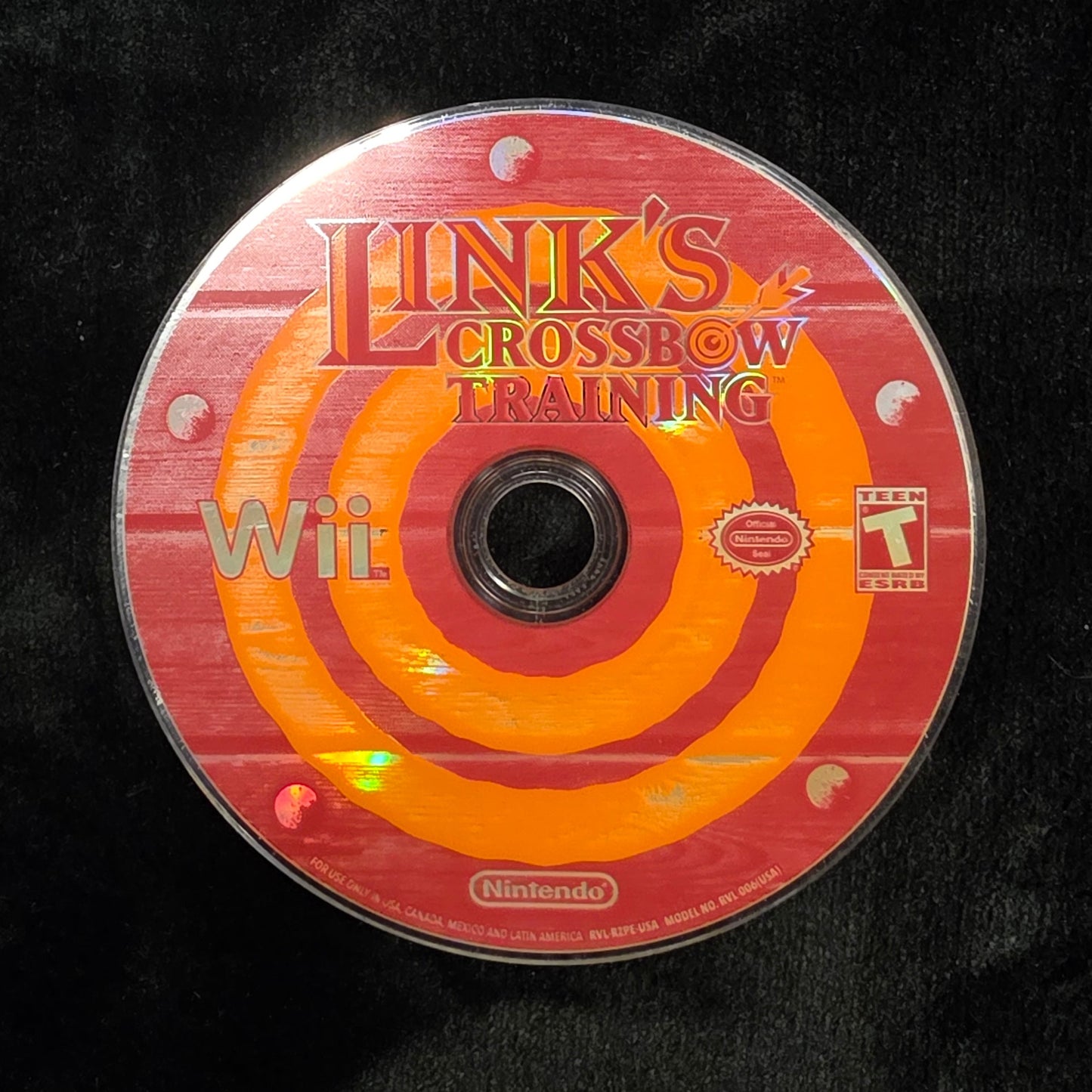 A Nintendo Wii game disc for 'Link's Crossbow Training' resting on a black plush fabric surface.