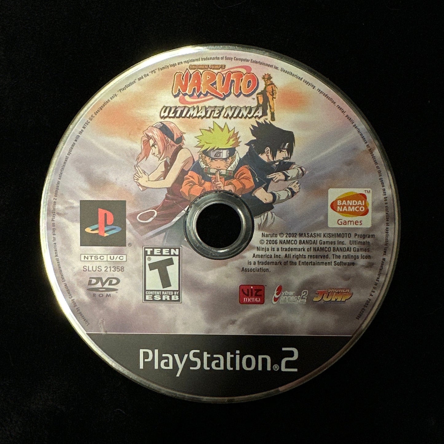 A PlayStation 2 game disc for Naruto: Ultimate Ninja, featuring Naruto and Sasuke Uchiha artwork, photographed on a black fabric background.