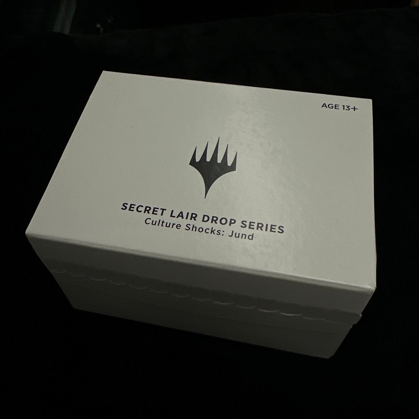White box with mtg logo and text on a dark background