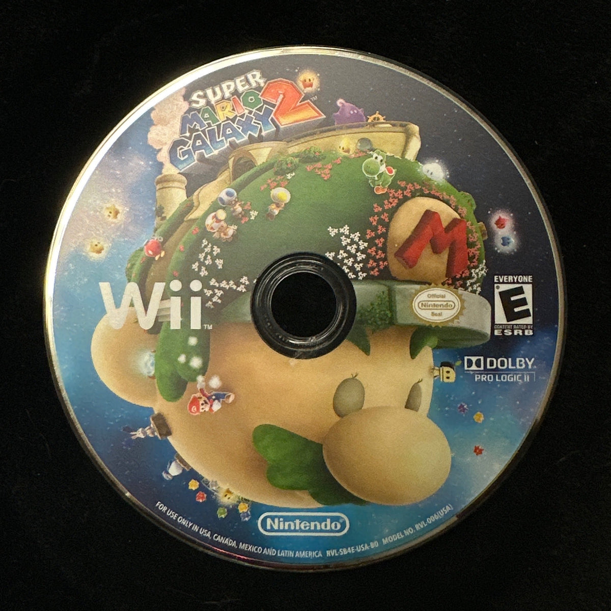 A Super Galaxy 2 video game disc for the Nintendo Wii, featuring Mario and other characters on the cover art, resting on a black surface.