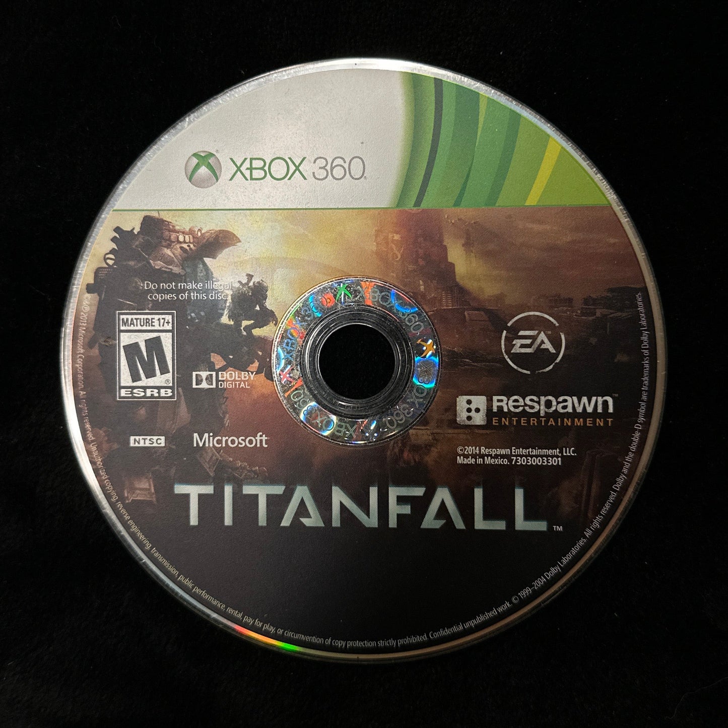 A used Xbox 360 game disc for Titanfall, featuring the game's cover art and logos for Xbox 360, Microsoft, EA, and Respawn, resting on a black surface.