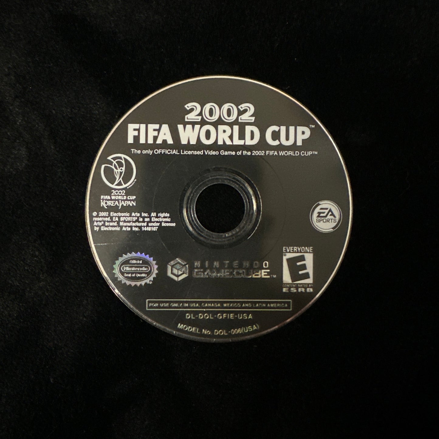 A 2002 FIFA World Cup video game disc for Nintendo GameCube, shown on a black textured background. The disc features white text and logos, including FIFA, Nintendo, and EA.