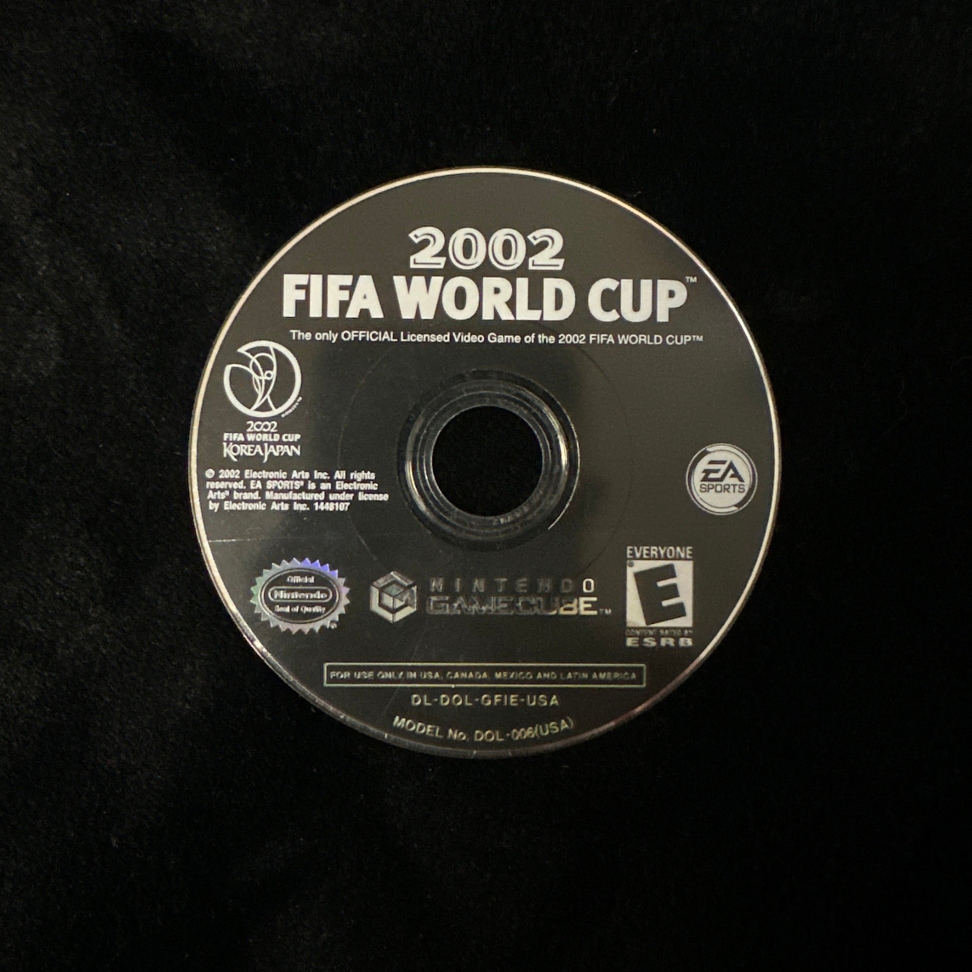 A 2002 FIFA World Cup video game disc for Nintendo GameCube, shown on a black textured background. The disc features white text and logos, including FIFA, Nintendo, and EA.