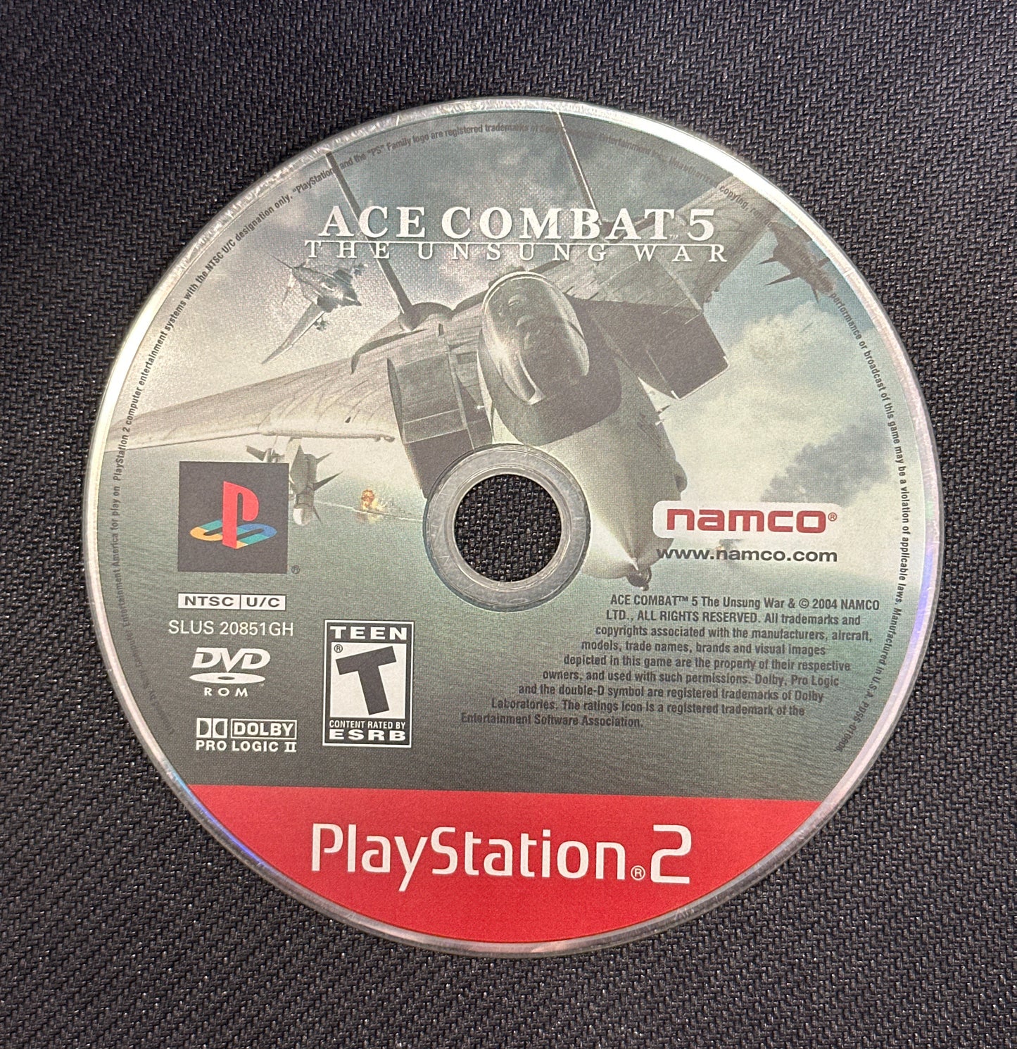 PlayStation 2 game disc for 'Ace Combat 5' on a dark textured background