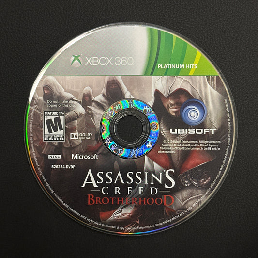Assassin's Creed Brotherhood game disc on a black surface