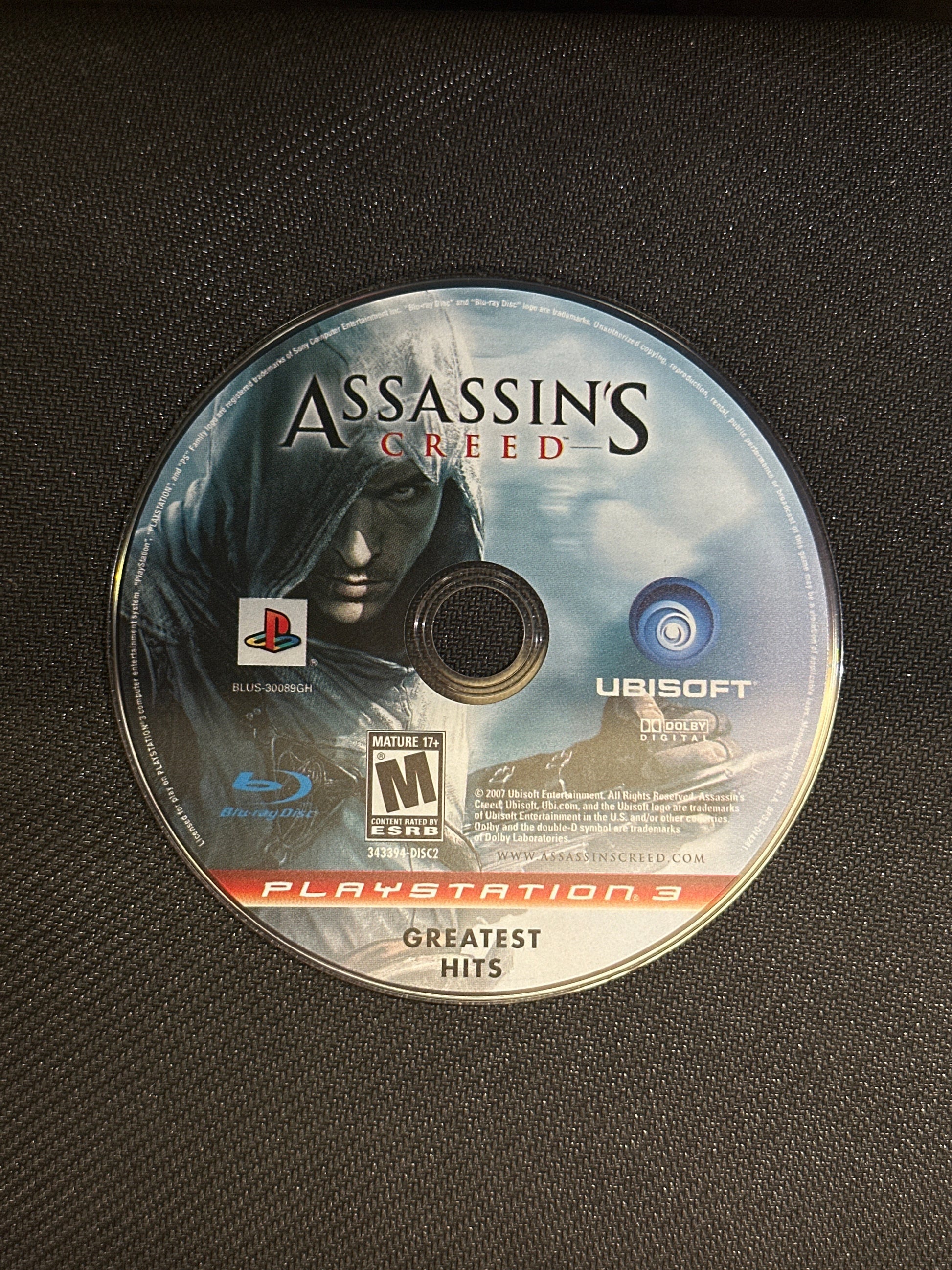 Assassin's Creed game disc on a black surface
