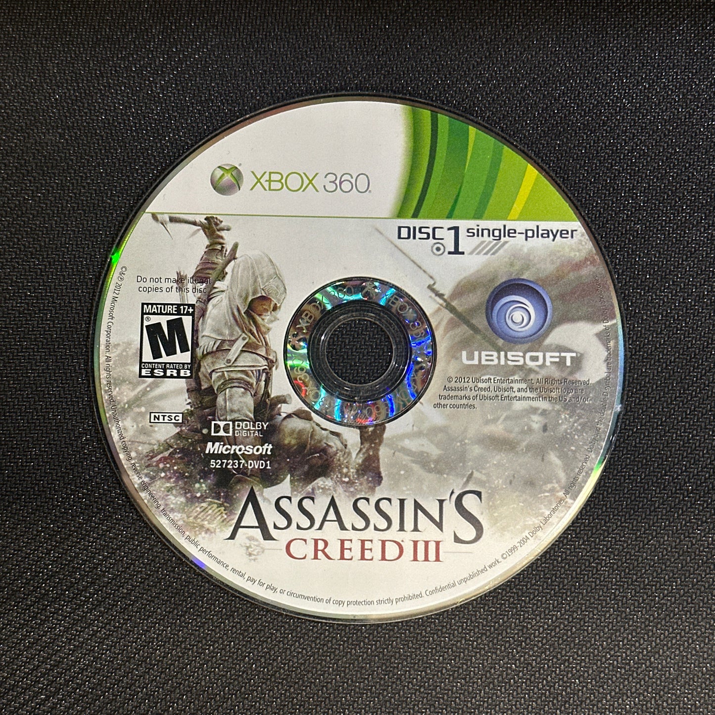 Game disc for 'Assassin's Creed III' on an Xbox 360 console.