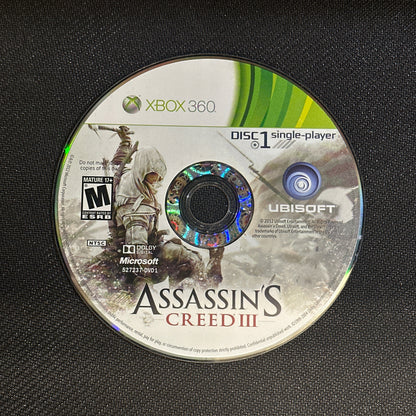 Game disc for 'Assassin's Creed III' on an Xbox 360 console.