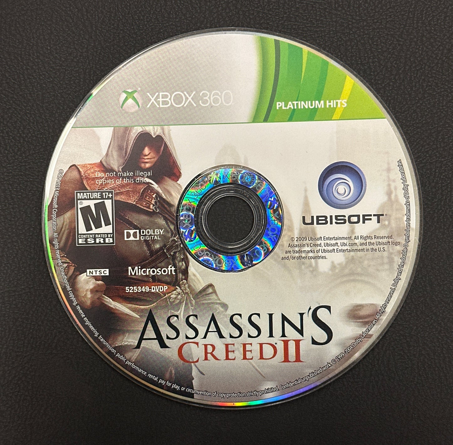Game disc for 'Assassin's Creed II' on Xbox 360 with Ubisoft logo.