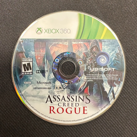 Assassin's Creed Rogue game disc for Xbox 360 on a dark surface