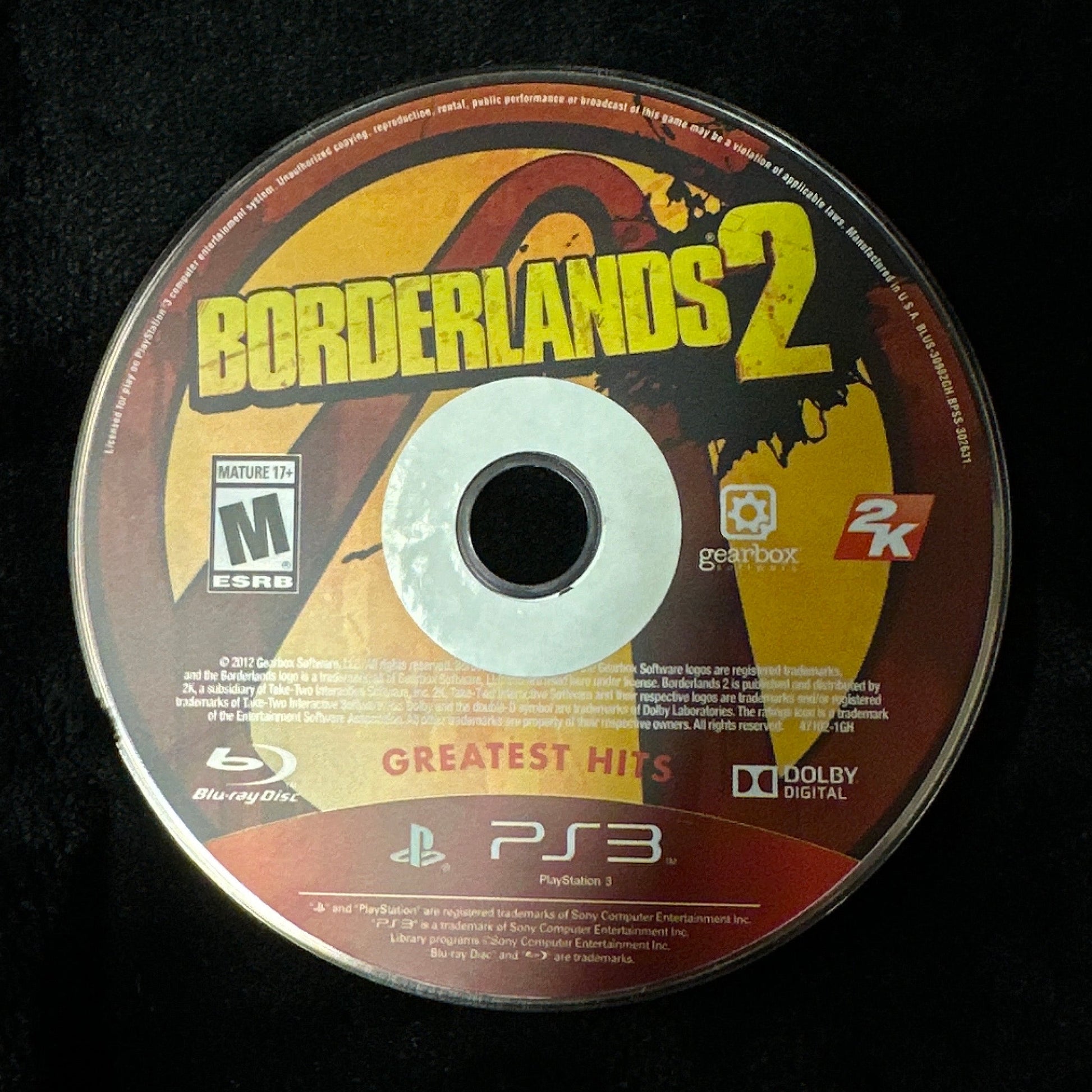 A PlayStation 3 disc for the video game Borderlands 2, displayed flat on a black fabric surface.