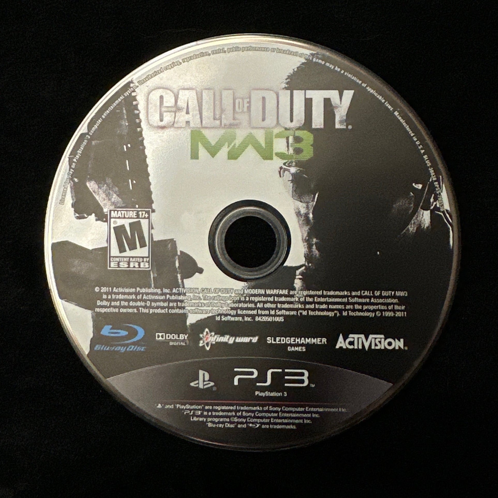 Call of Duty: Modern Warfare 3 PS3 game disc for PlayStation 3, displayed on a black fabric surface.