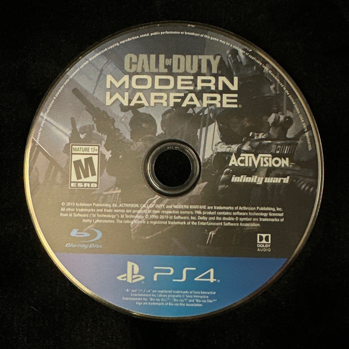 A Call of Duty: Modern Warfare PlayStation 4 game disc resting on a black fabric surface.