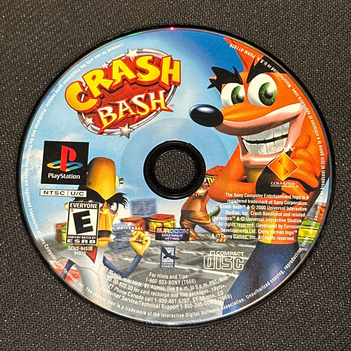 Game disc for 'Crash Bash' on a black textured surface