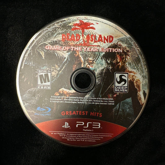 A PlayStation 3 game disc for 'Dead Island: Game of the Year Edition' in the Greatest Hits bundle, resting on a black textured surface.