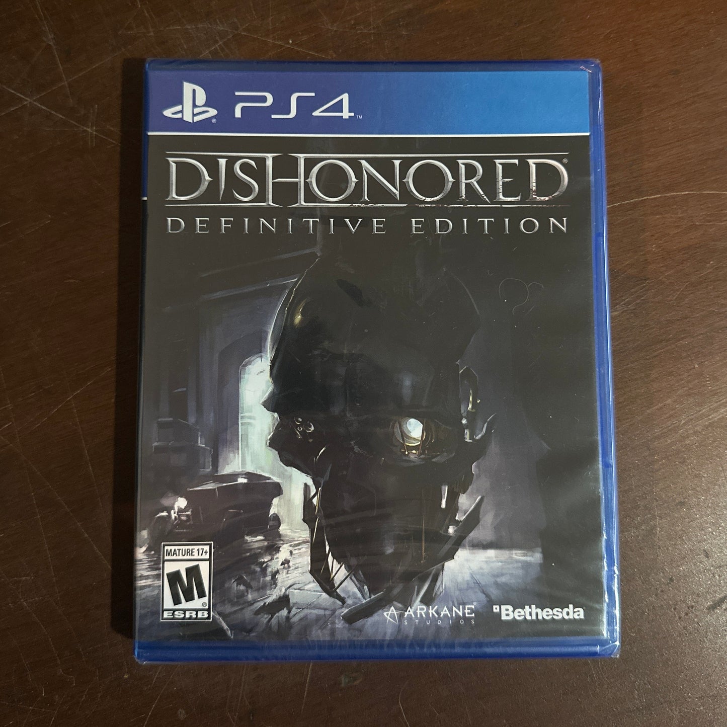 Game case for 'Dishonored: Definitive Edition' on a wooden surface