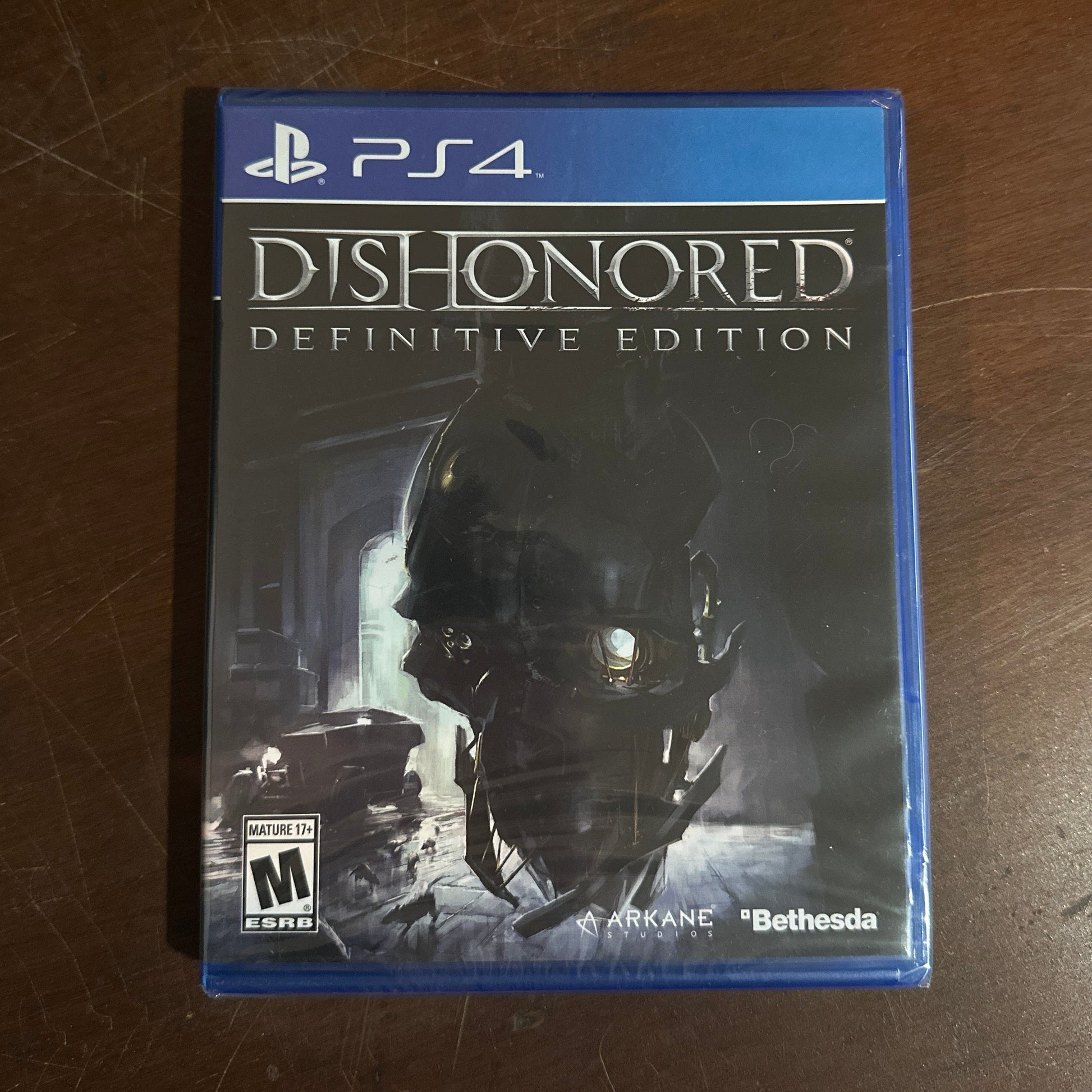 Game case for 'Dishonored: Definitive Edition' on a wooden surface