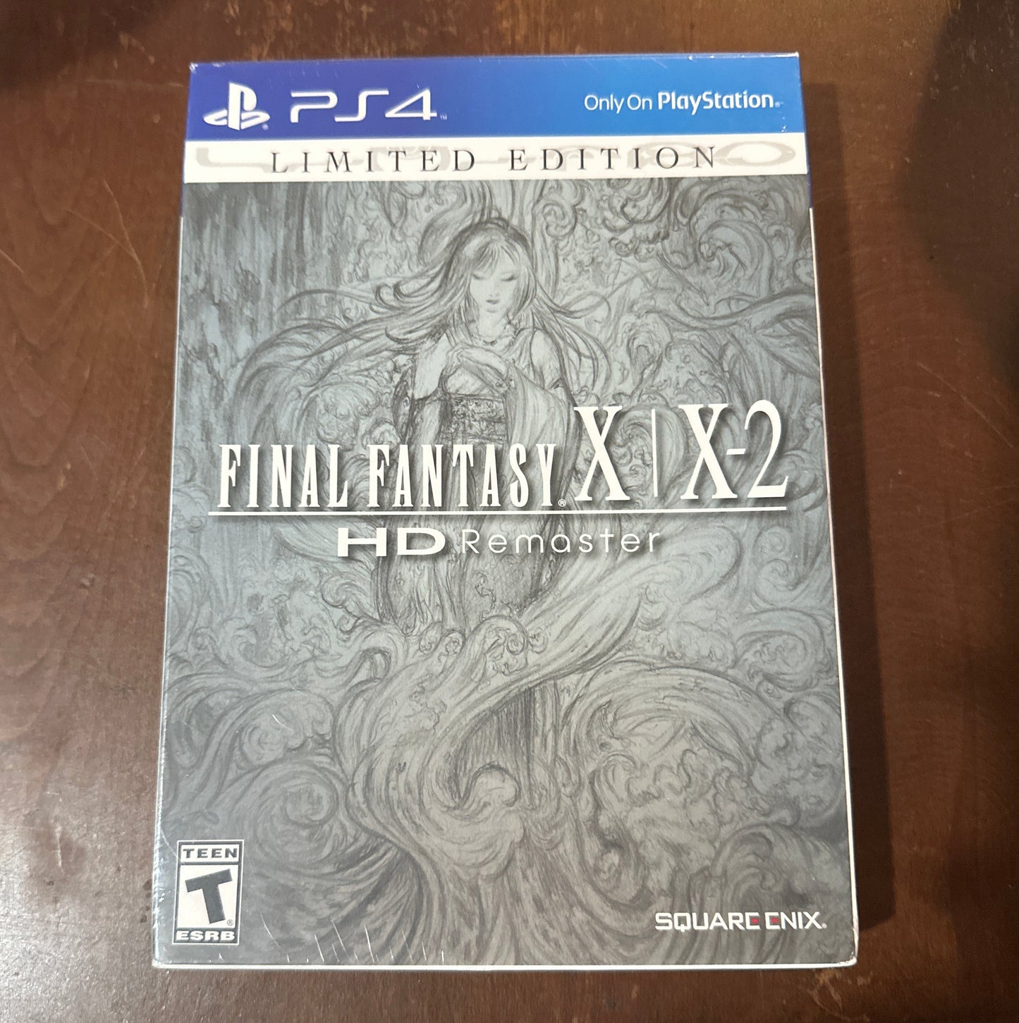 PlayStation 4 game case for 'Final Fantasy X/X-2 HD Remaster' on a wooden surface