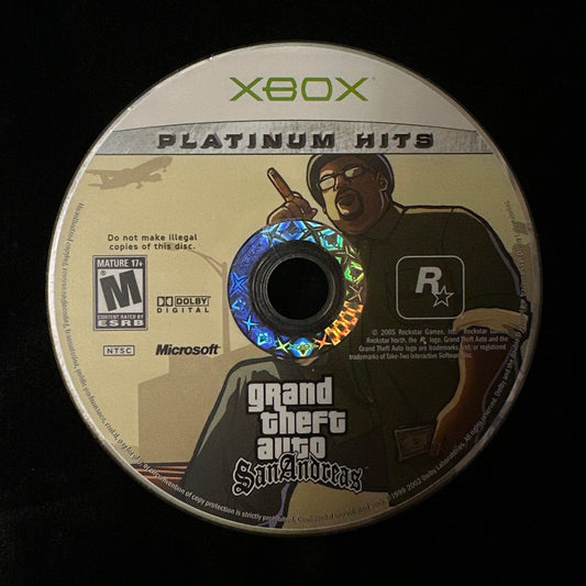 An Xbox Platinum Hits Grand Theft Auto: San Andreas game disc on a black background.