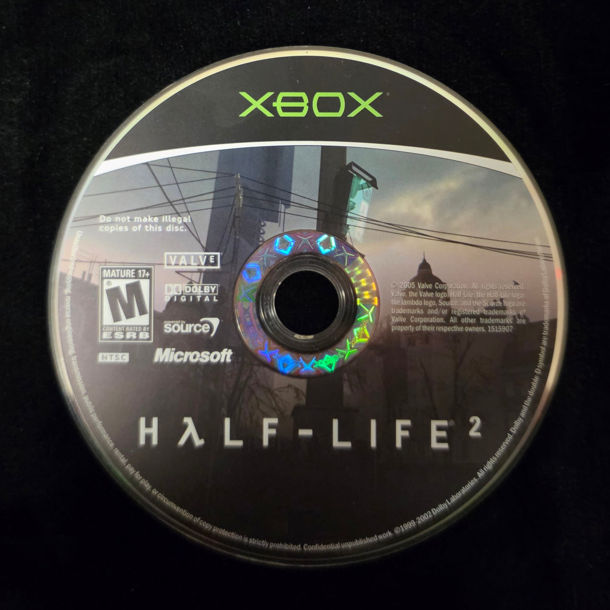An Xbox Half-Life 2 game disc resting on a black fabric surface, with the Xbox logo and Half-Life 2 title clearly visible.