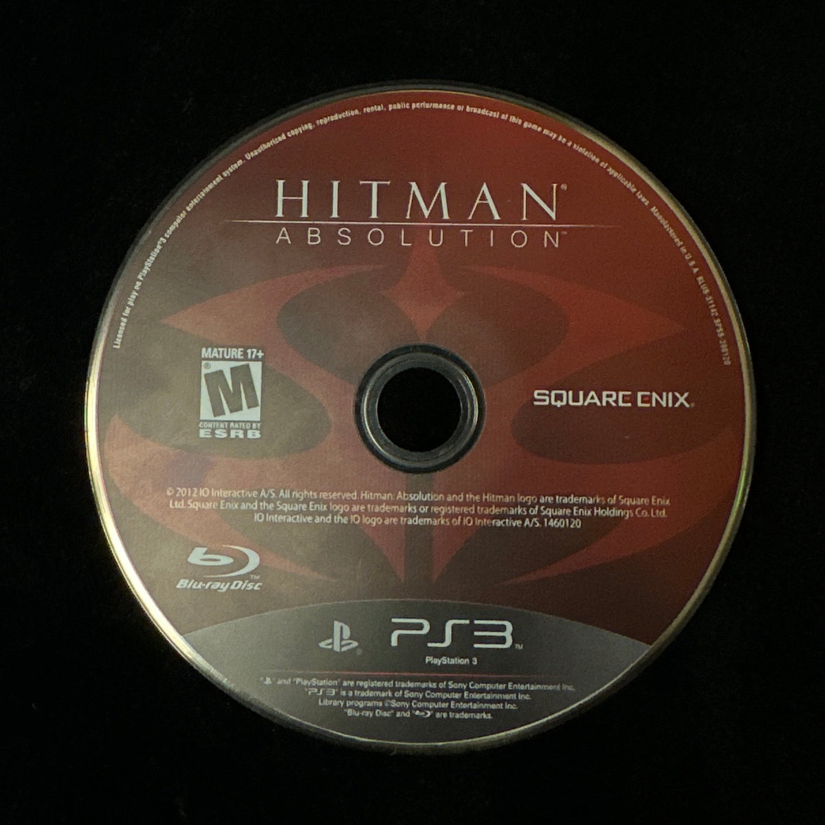 A PlayStation 3 game disc for 'Hitman Absolution' by Square Enix, displayed on a black surface.