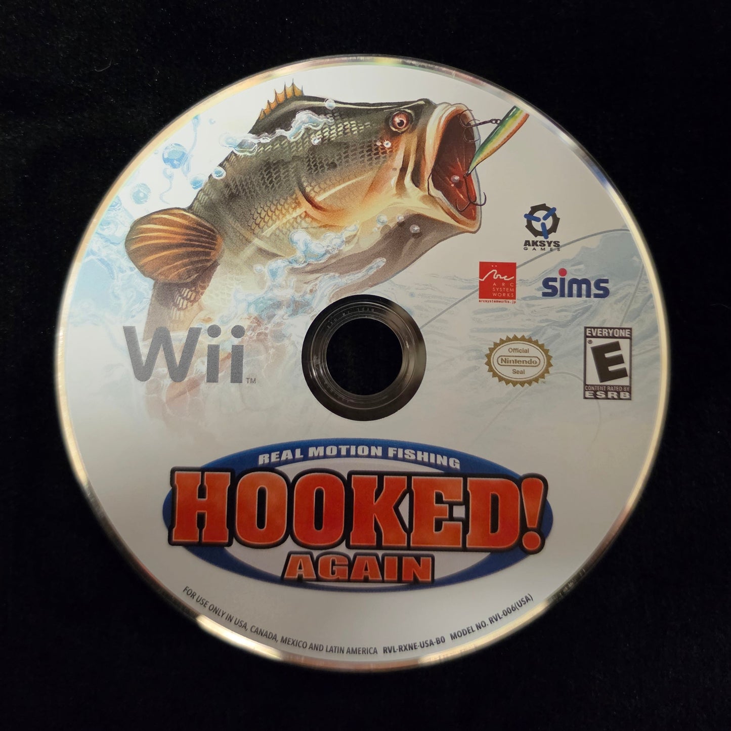 A Wii game disc for 'Hooked! Again' resting on a black surface, showing the bass fish cover art and logos for Nintendo, simS, and ESRB.