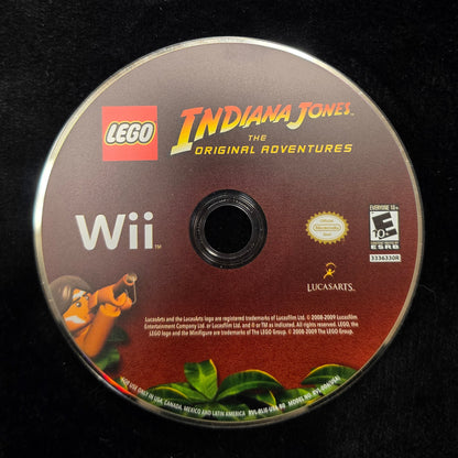 A LEGO Indiana Jones The Original Adventures Wii game disc for the Nintendo Wii, resting on a black fabric surface.