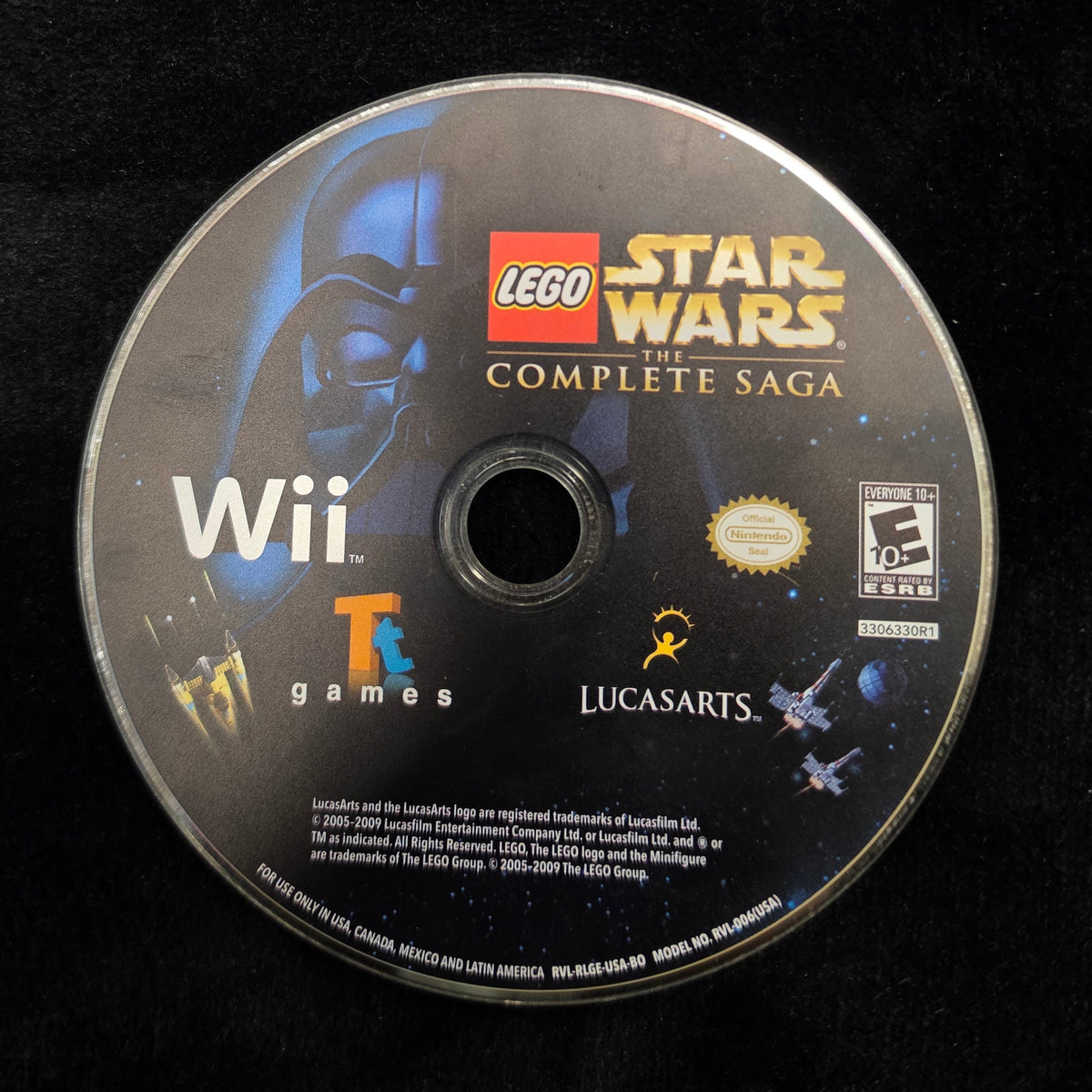 A Wii game disc for LEGO Star Wars: Complete Saga, featuring artwork of Darth Vader and the LEGO Star Wars logo, resting on a black textured surface.