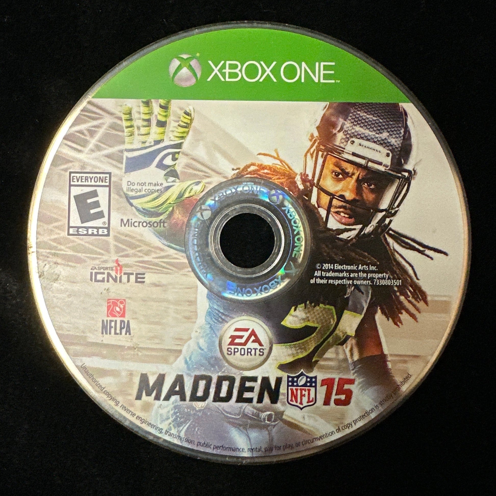 An Xbox One game disc for Madden NFL 15, featuring a football player on the cover, photographed against a black background.