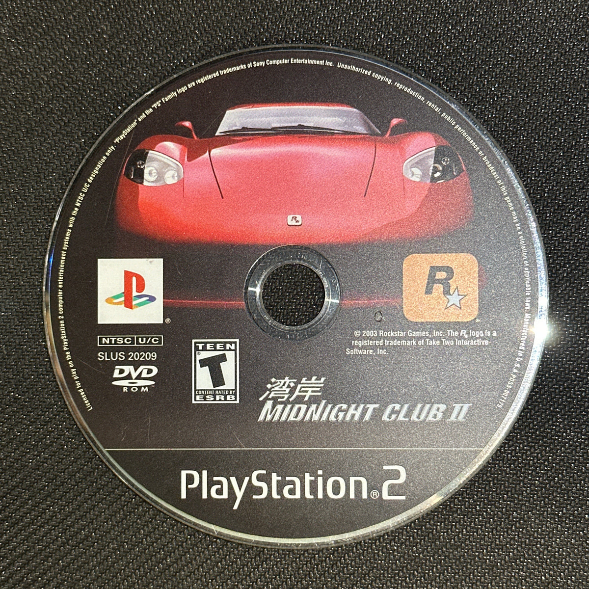 PlayStation 2 game disc with a red car on a black textured background