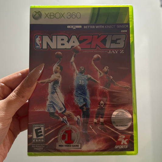 Hand holding a 'NBA 2K13' game case for Xbox 360 against a neutral background