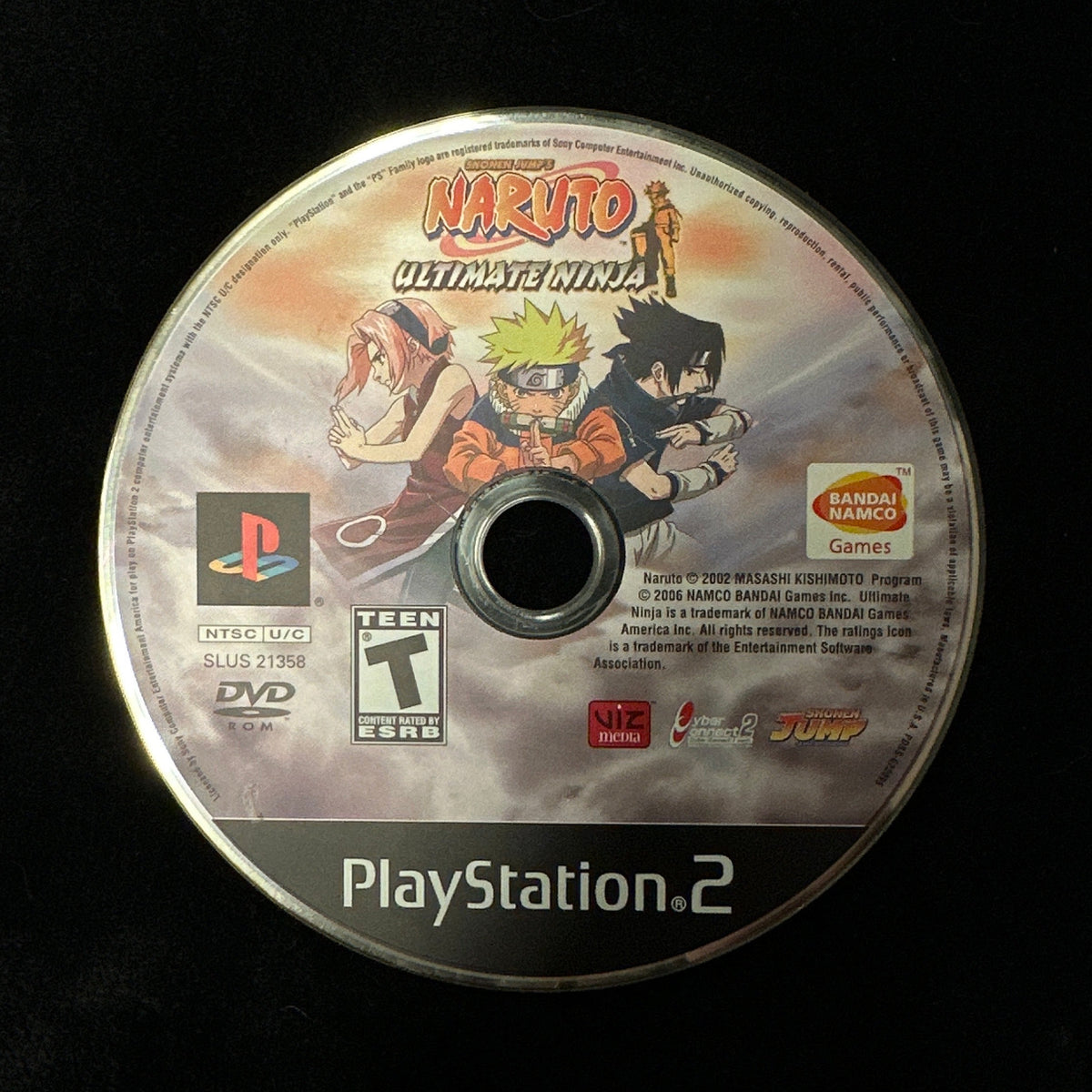 A PlayStation 2 game disc for Naruto: Ultimate Ninja, featuring Naruto and Sasuke Uchiha artwork, photographed on a black fabric background.