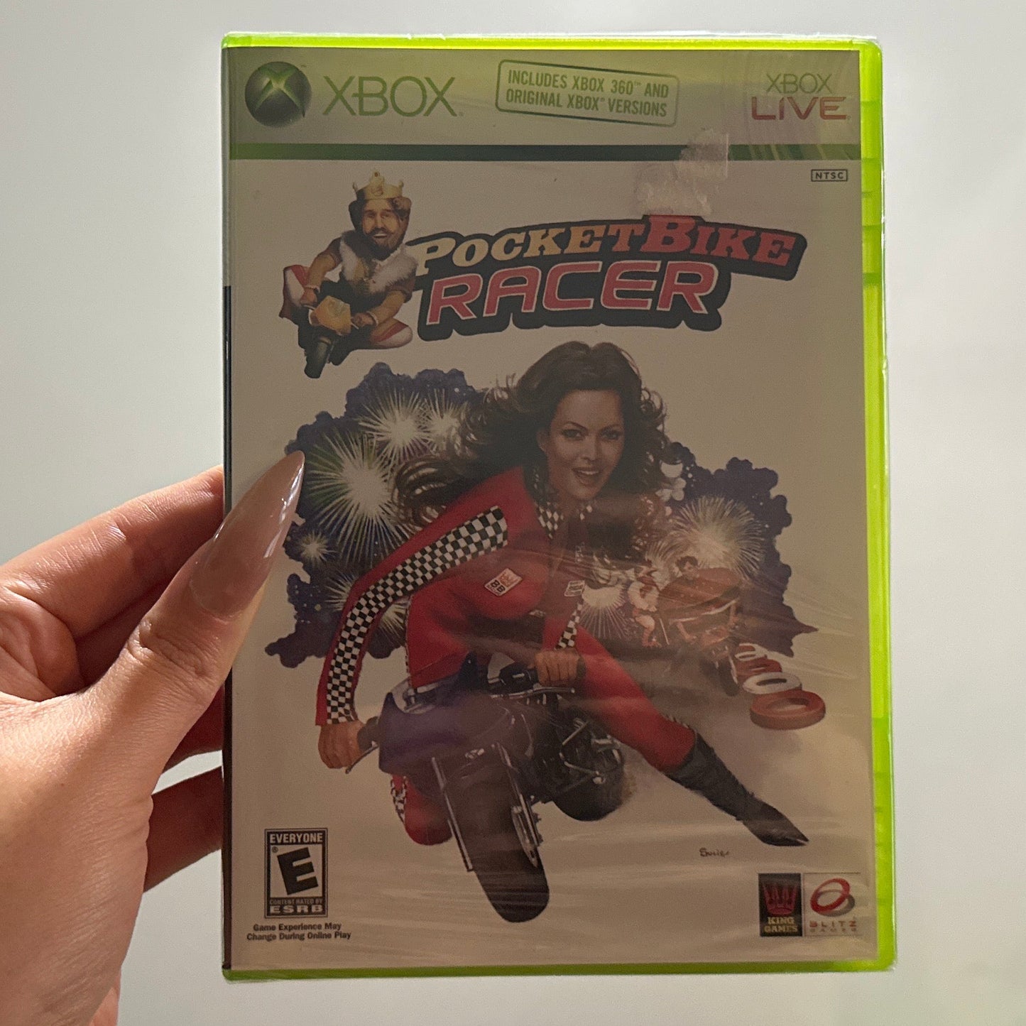 Hand holding a 'Pocket Bike Racer' Xbox game case against a white wall.