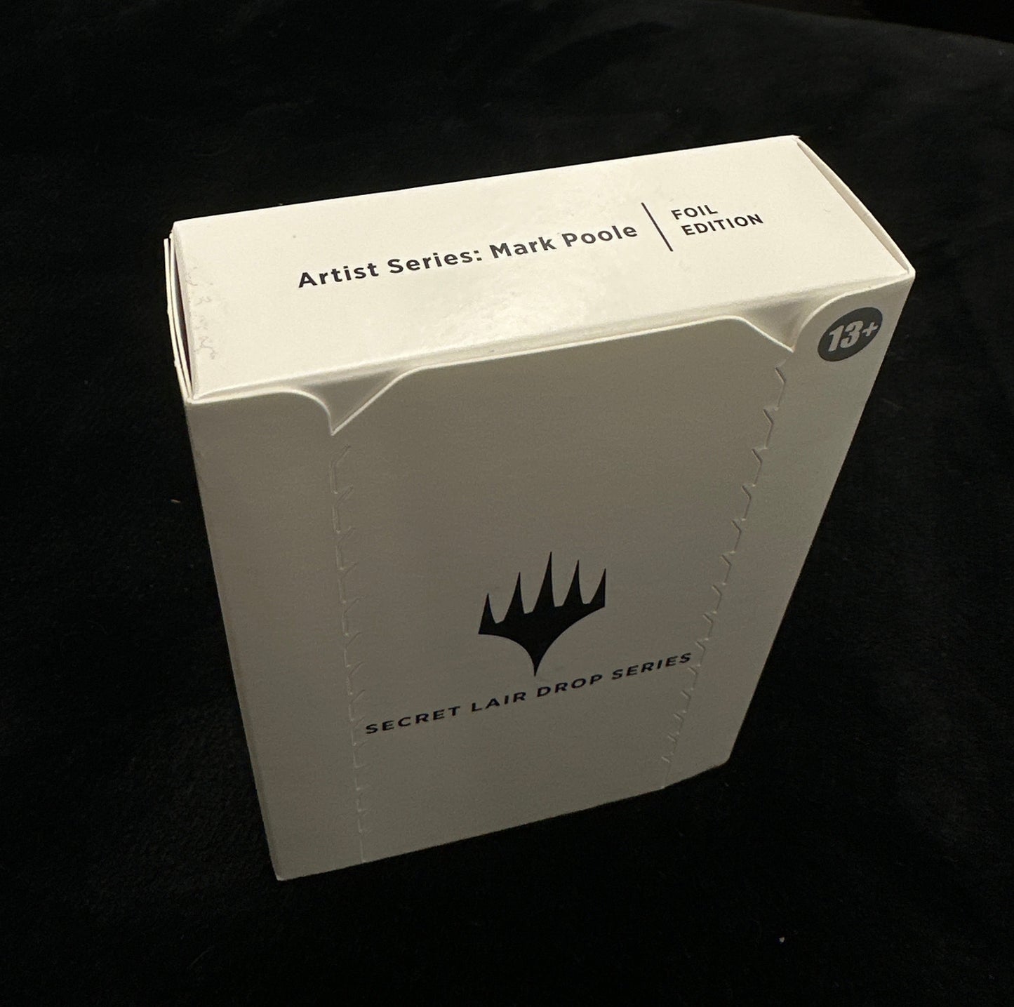 White box with mtg logo on a dark surface