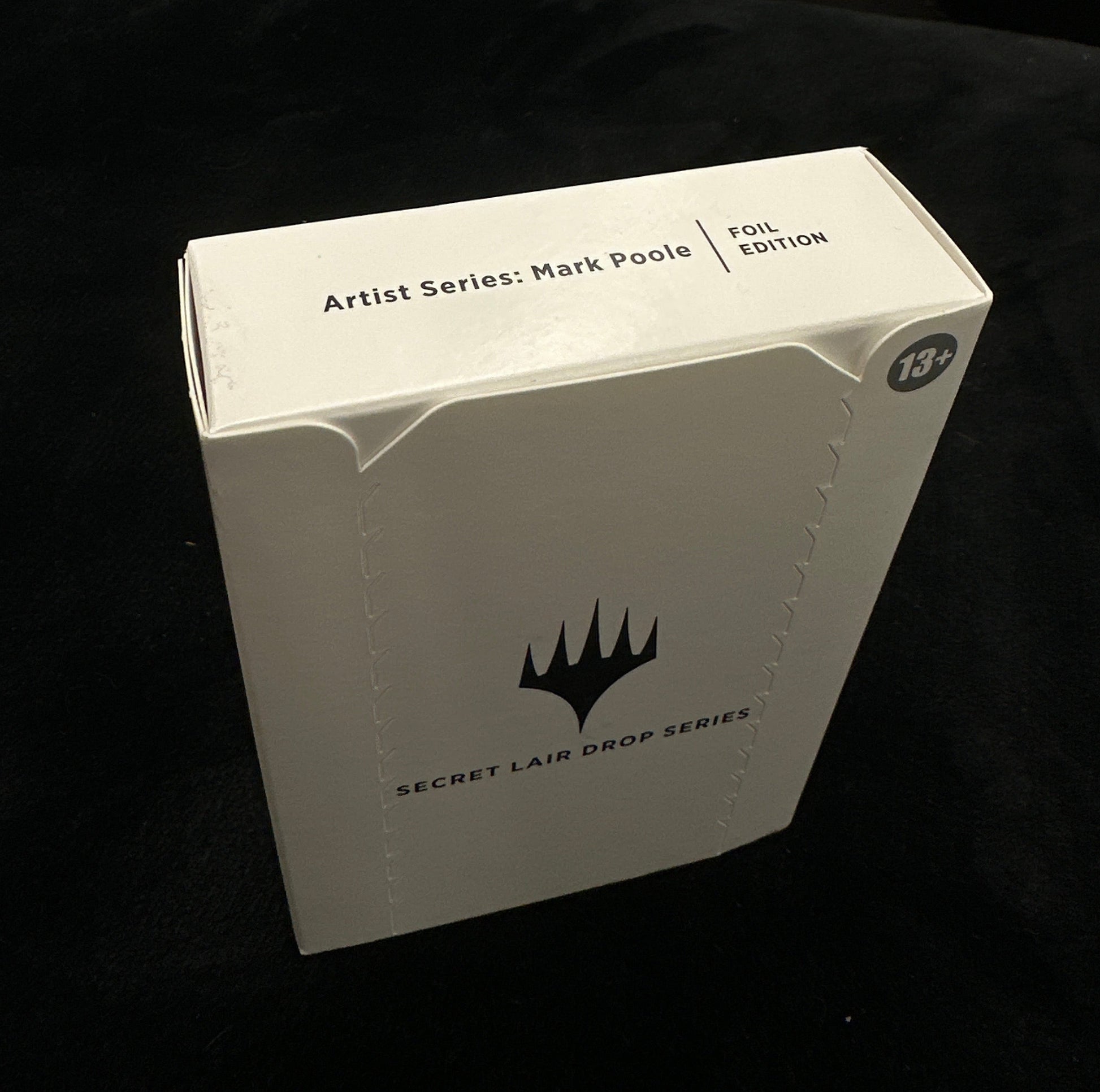 White box with mtg logo on a dark surface
