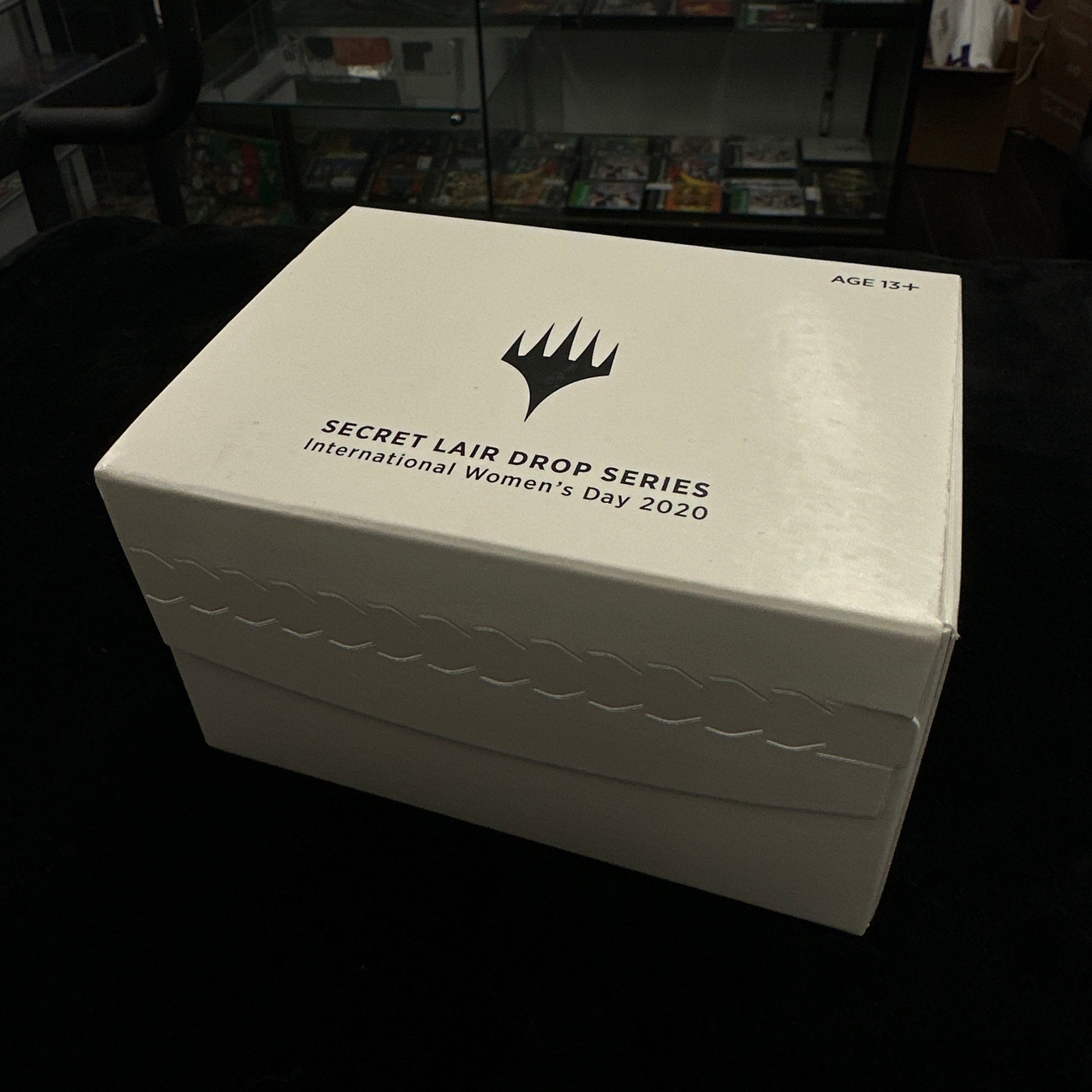 White box with mtg logo and text on a dark background