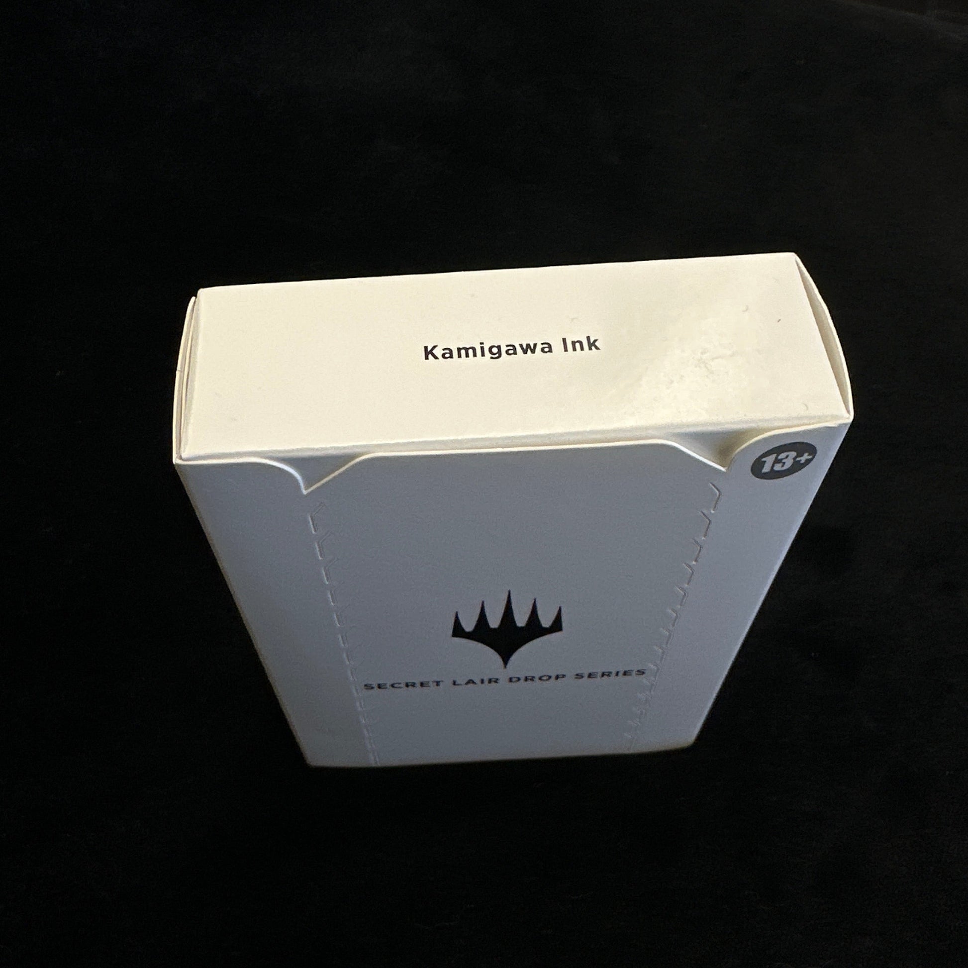 White rectangular box with black text and mtg logo on a dark background