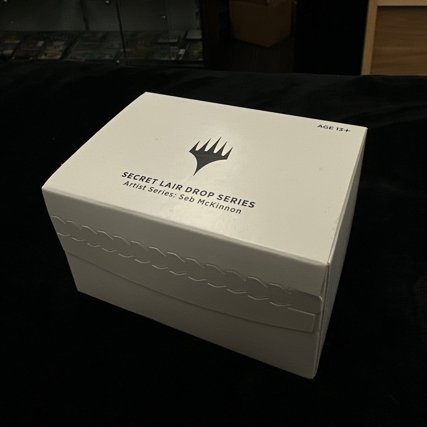 White box with mtg logo on a dark background