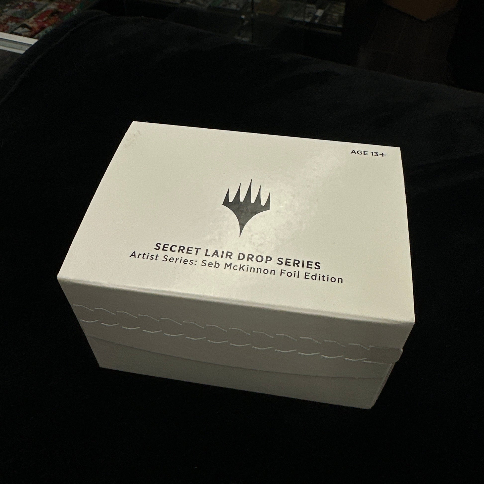 White box with text and mtg logo on a dark background