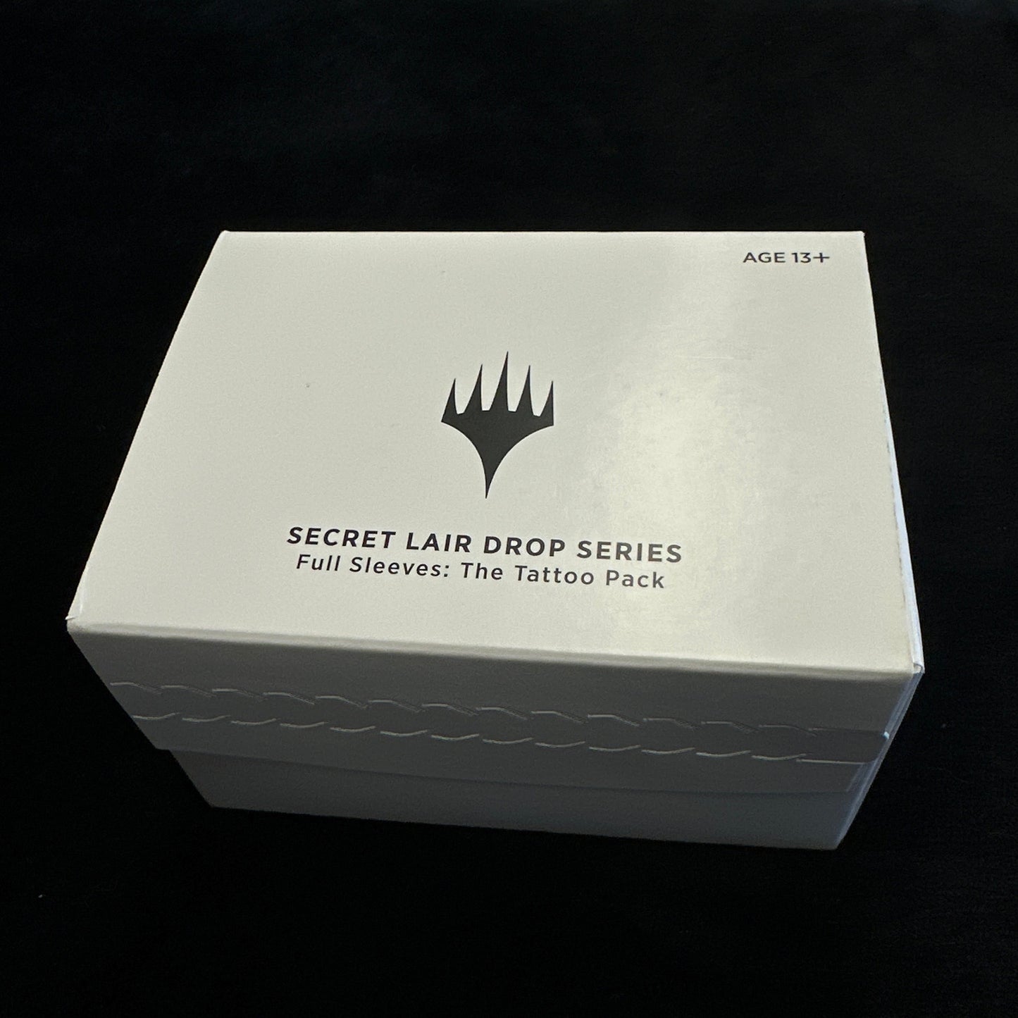 White box with black text and mtg logo on a dark background