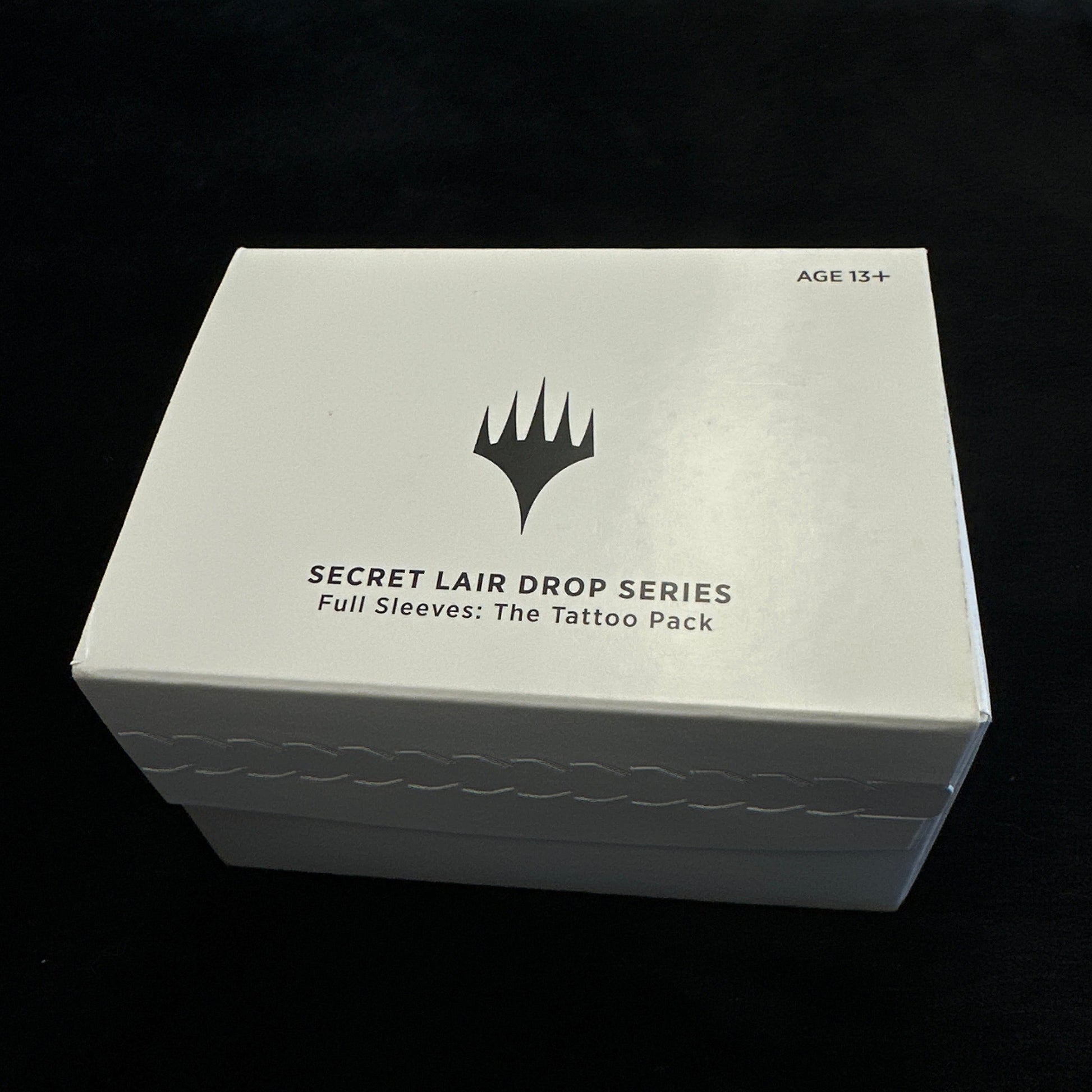 White box with black text and mtg logo on a dark background