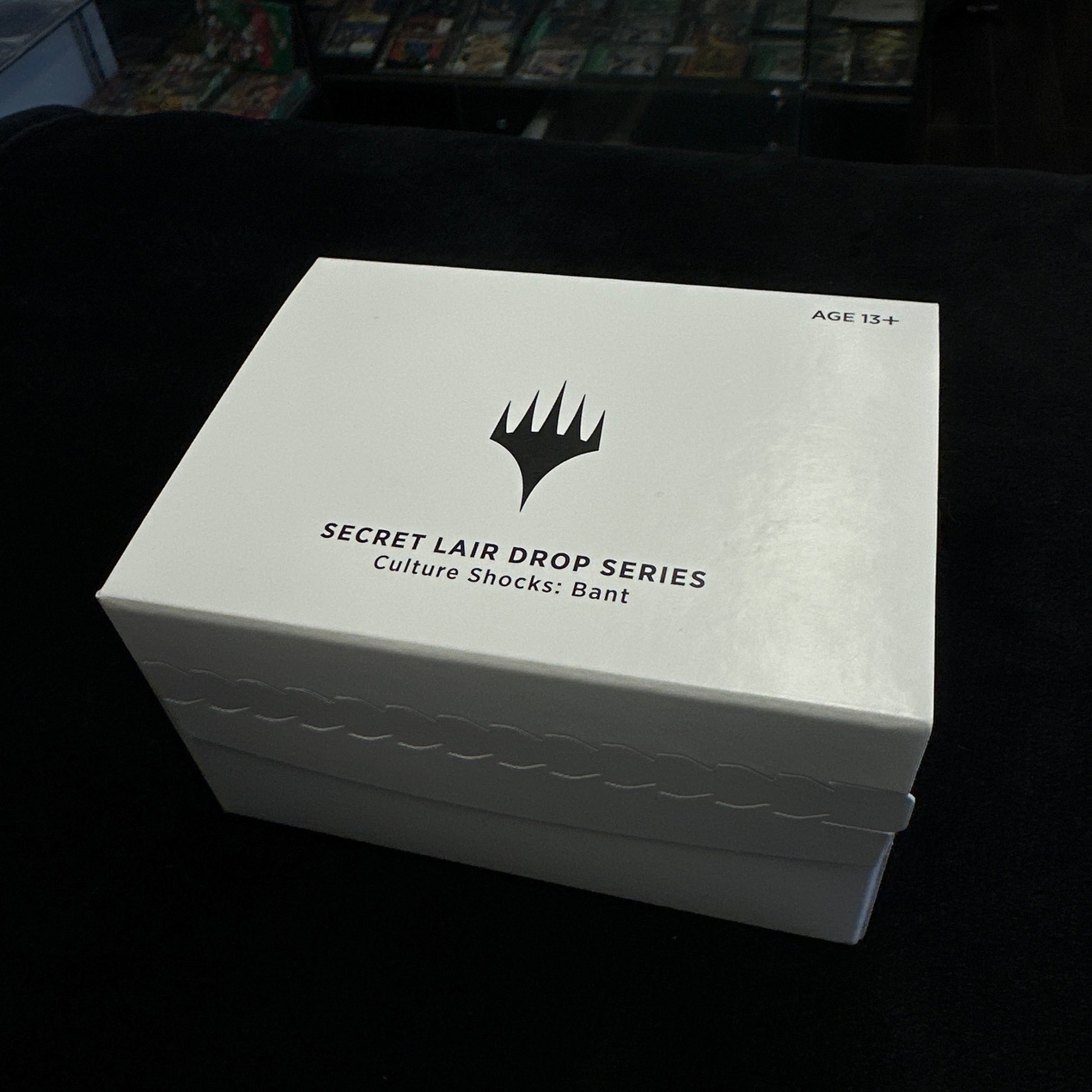 White box with black text and mtg logo on a dark background