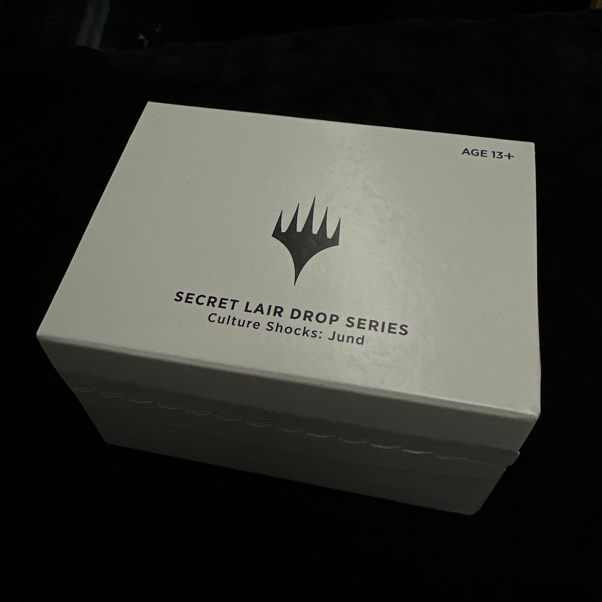 White box with mtg logo and text on a dark background
